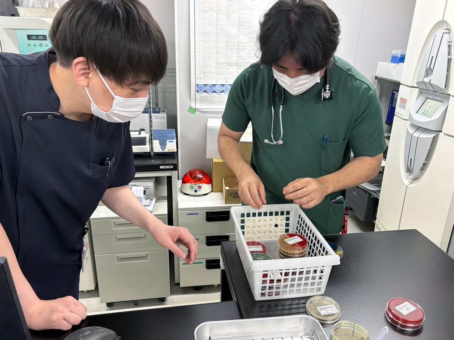 検査室でスタッフと培養皿を確認する山浦義貴医師